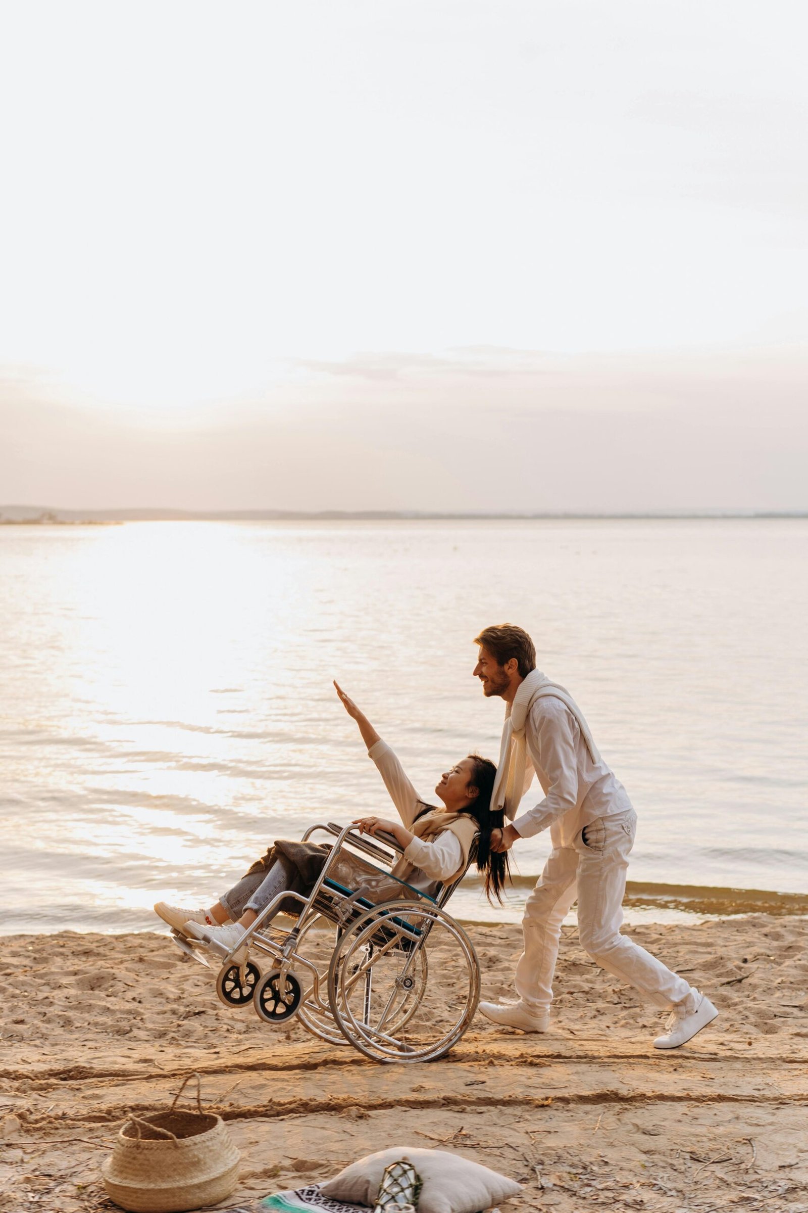 Woman in a wheelchair at the beach with her husband who is her caregiver