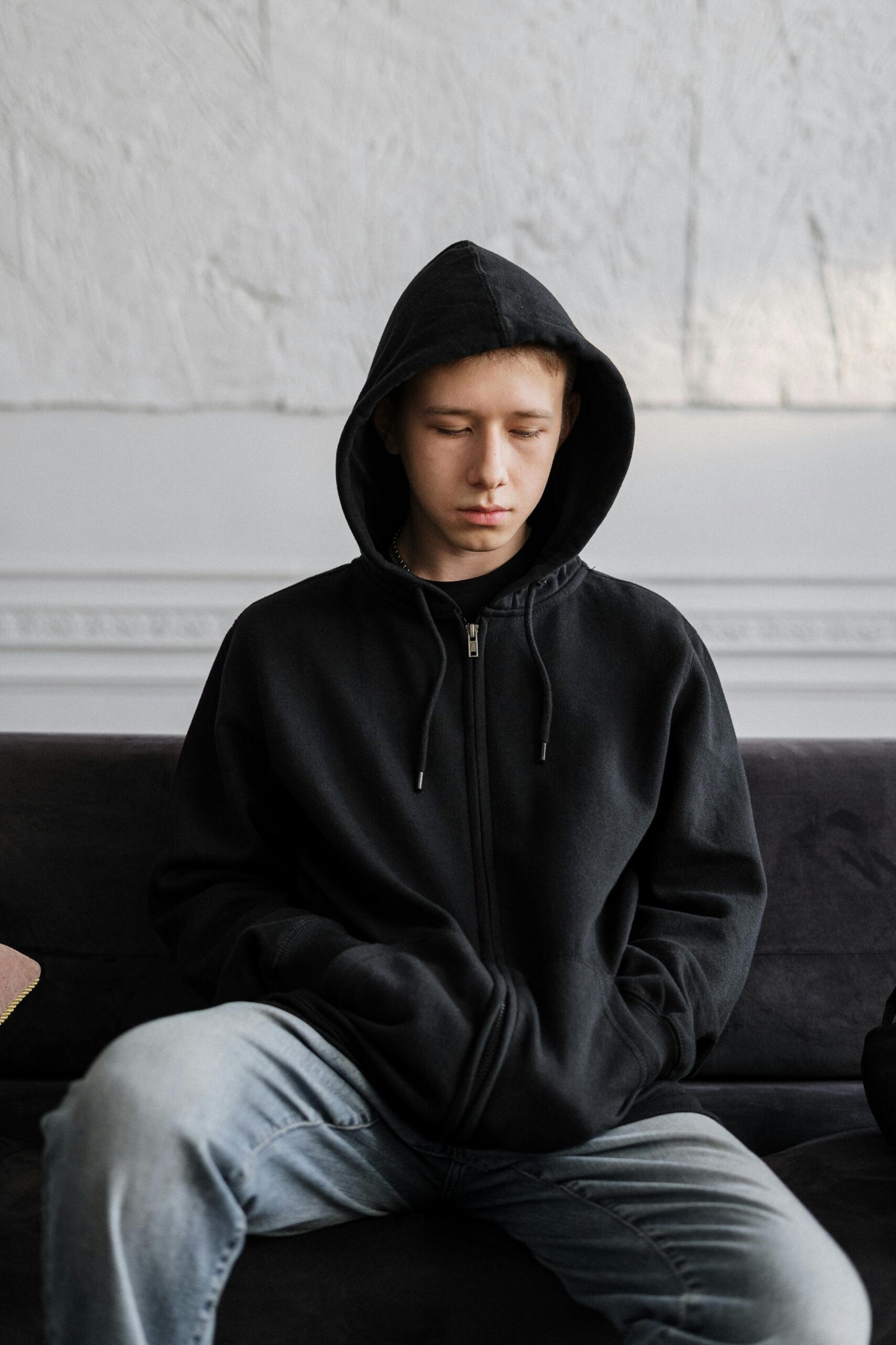 Man in black hoody sitting on a couch and processing a breakup