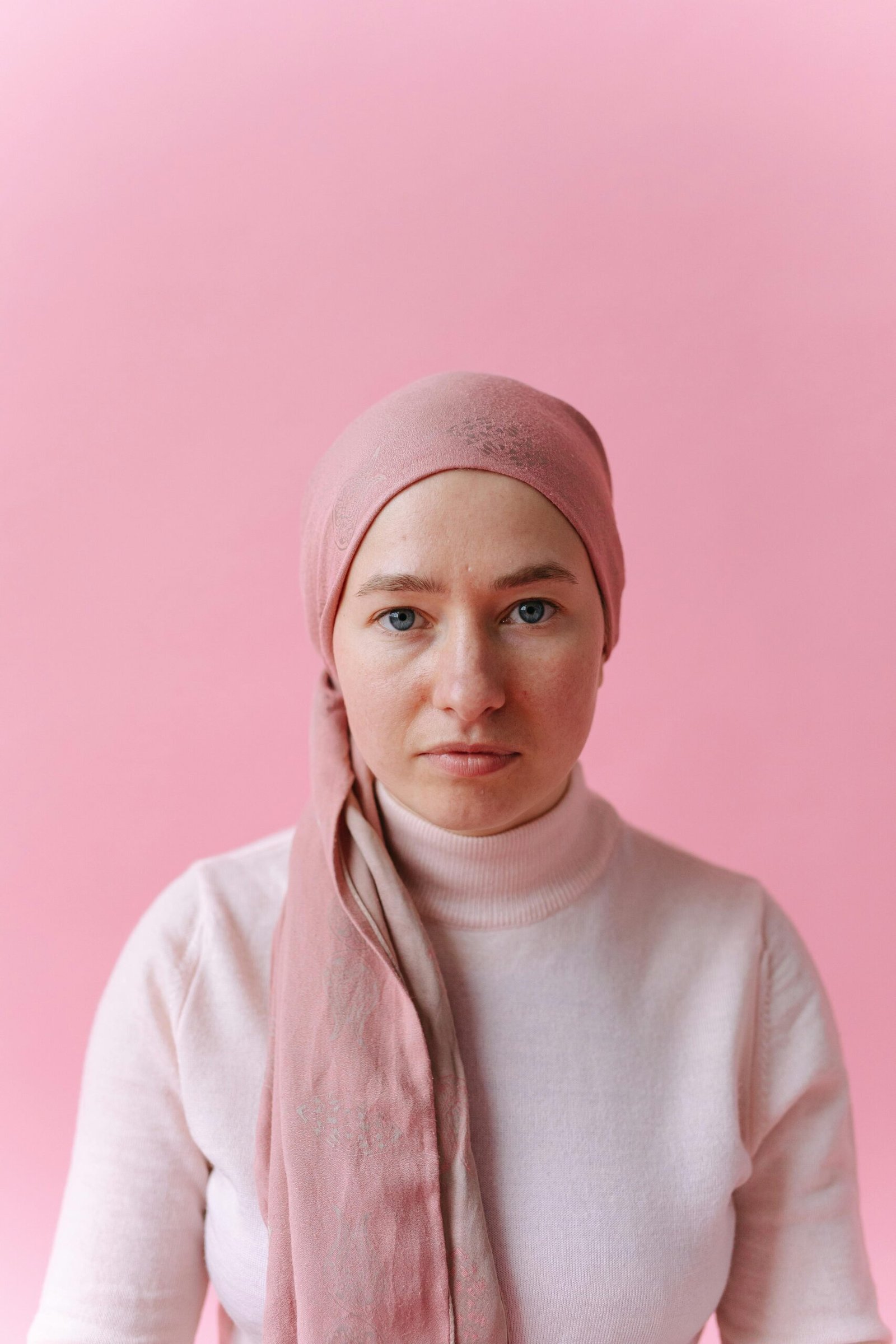 Woman with a pink scarf covering her head after losing her hair to cancer