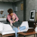 Two women share a caring embrace in a cozy, modern living room, embodying support for a terminally ill cancer sufferer