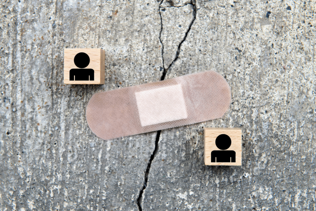 Cracks in concrete covered with a bandaid, representing a crack in a relationship