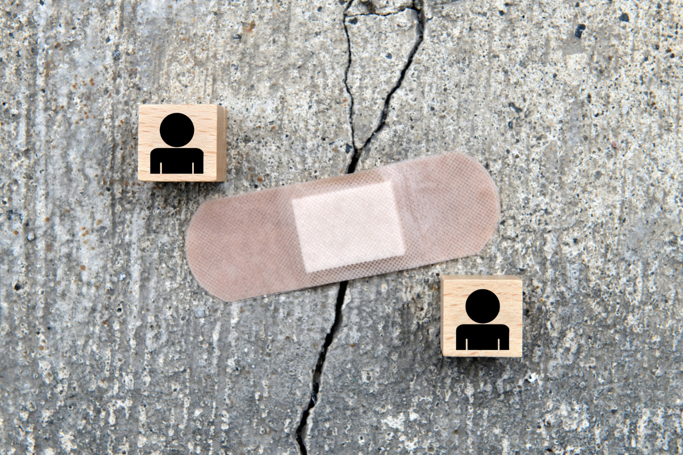 Cracks in concrete covered with a bandaid, representing a crack in a relationship