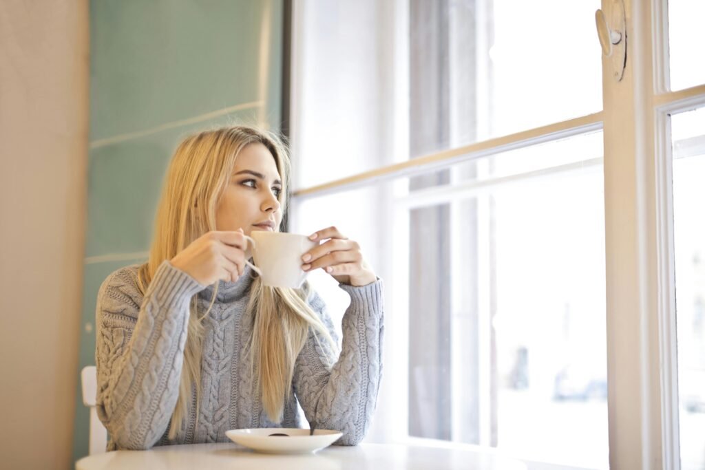Woman on her own drinking coffee and looking out the window