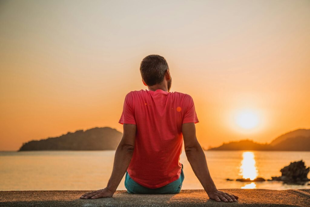 Man in red shirt staring at the ocean