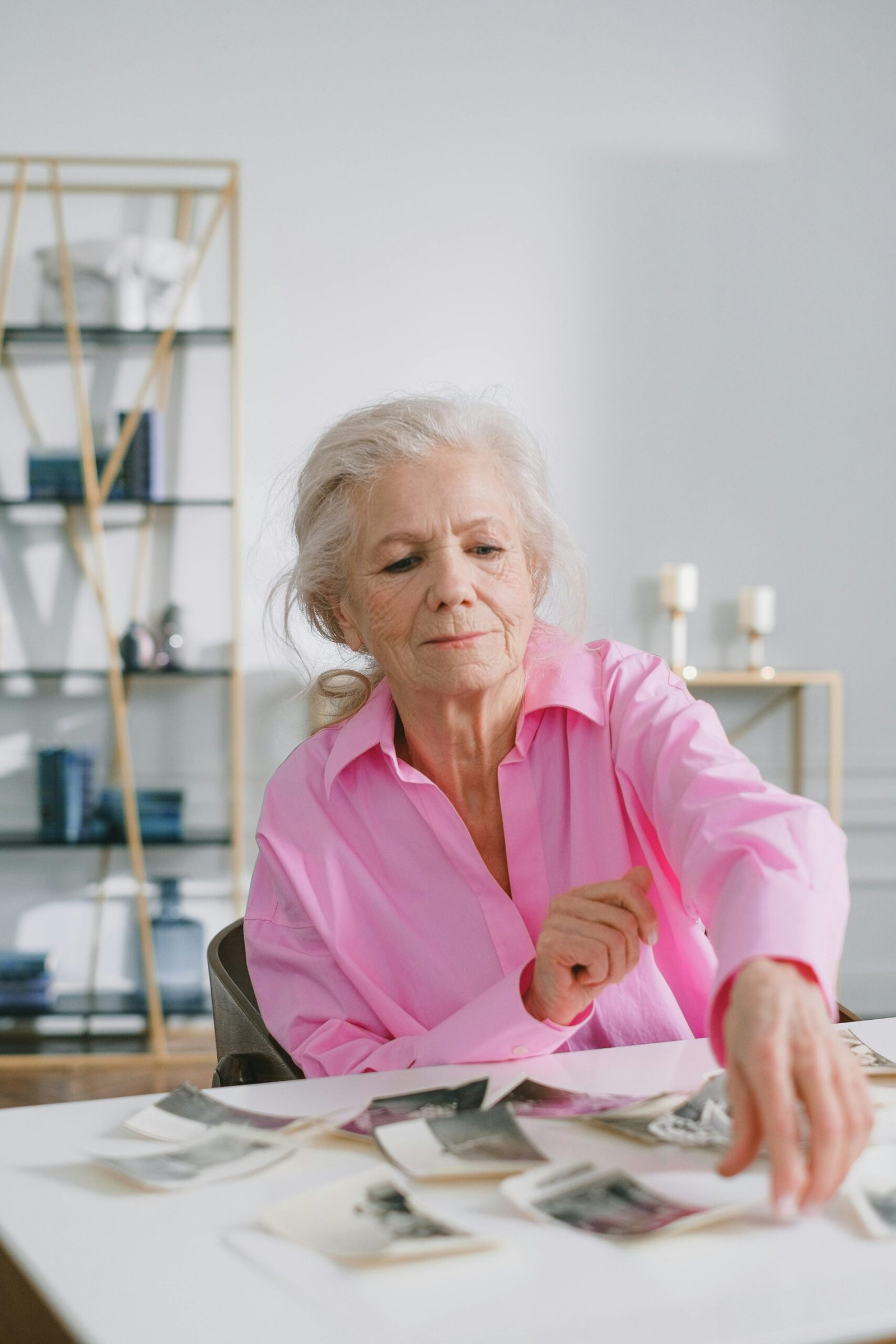 An elderly woman in a pink shirt sorting through photos as part of a memory project for dementia