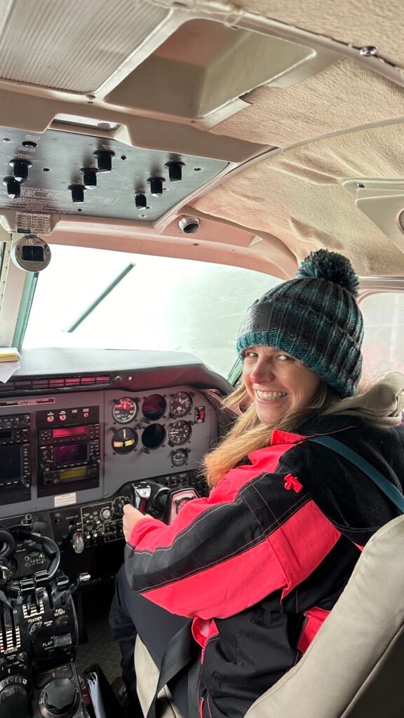 A picture of Tracy Rattray, Owner and registered counsellor at the Beach Haven in clarkson, flying a small plane on a trip to remote parts of Alaka