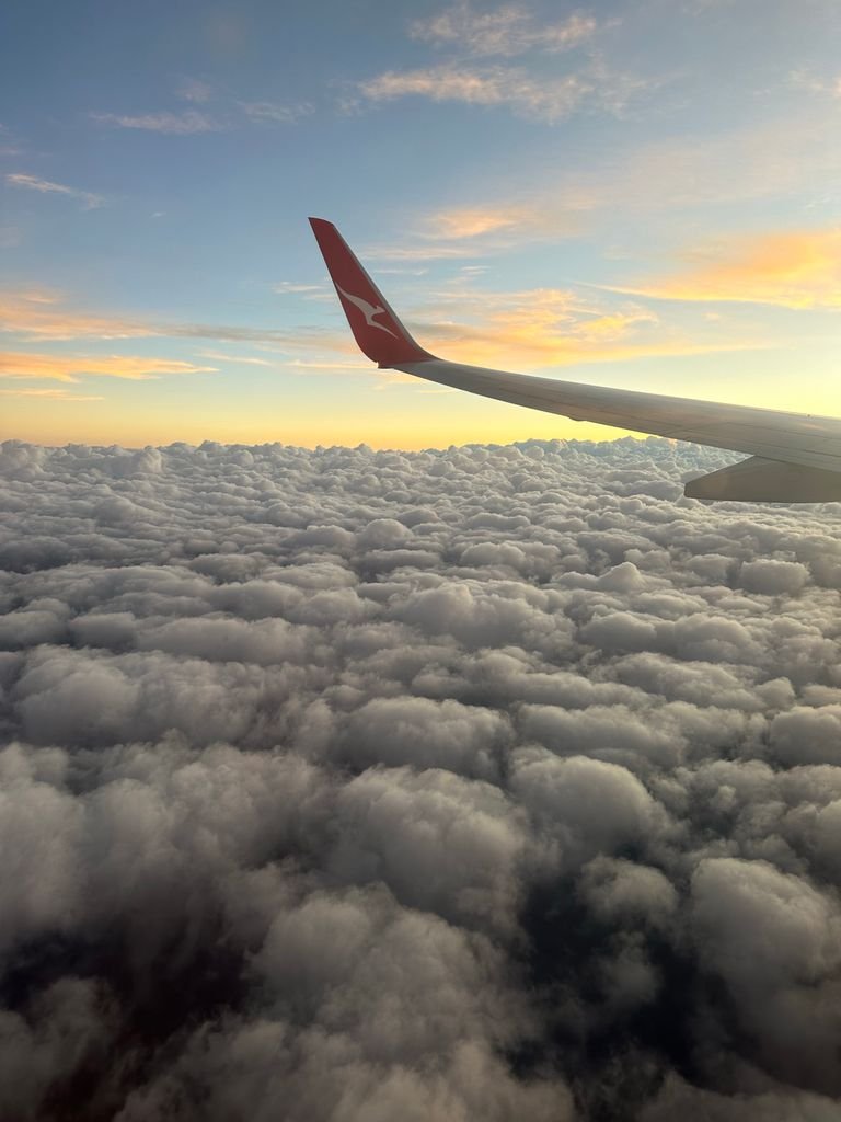 Aerial view of a plane wing amidst fluffy clouds during FIFO flight in Australia